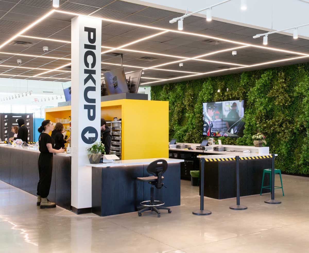 Bright dispensary interior with pickup counter and green living wall